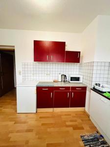 Una cocina con gabinetes rojos y blancos y un microondas. en Geräumige Wohnung Nähe HBF, en Eisenach