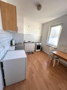 Una cocina con electrodomésticos blancos y suelo de madera. en Geräumige Wohnung Nähe HBF, en Eisenach
