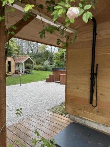 an open door of a wooden building with a yard at Idyllic cottage with wellness facilities in Alveringem