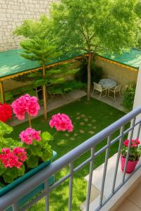Un balcón con un jardín con flores rosas y una mesa. en Noonbir Alaçatı otel, en Cesme