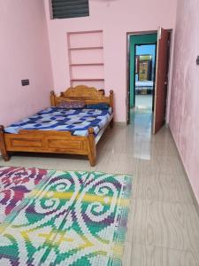 ein Schlafzimmer mit einem Bett und einem Teppich auf dem Boden in der Unterkunft Siva Sandhy Guset House in Tiruvannāmalai