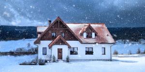 a small house in the snow in a field at Przystanek Lasówka in Lasowka