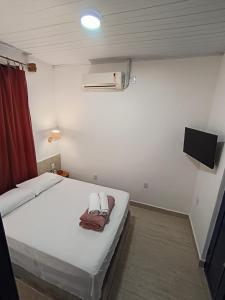 a bedroom with a white bed and a flat screen tv at Pousada Andarai in Andaraí