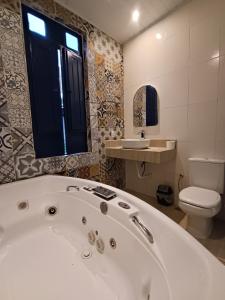 a bathroom with a white tub and a toilet at Pousada Andarai in Andaraí