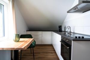 a kitchen with white cabinets and a wooden table at Apartment Manu in Inzlingen