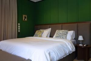 a bedroom with a large white bed with green walls at The Libreville in Abuja +8 photos