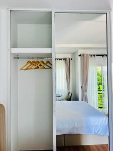una camera da letto con un letto bianco e uno specchio di Sarona House 4 a Ban Thalat Choeng Thale