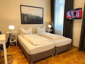 two beds in a room with a tv on the wall at Wien West Home in Vienna
