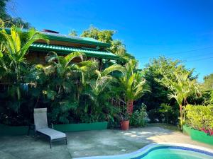 a house with a chair next to a swimming pool at Finca Los Mangos in Manuel Antonio