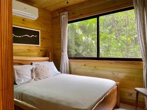 a bed in a wooden room with a large window at Finca Los Mangos in Manuel Antonio +64 photos