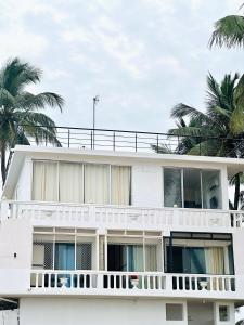 een wit gebouw met palmbomen op de achtergrond bij SALT classic beach resort in Kālapettai