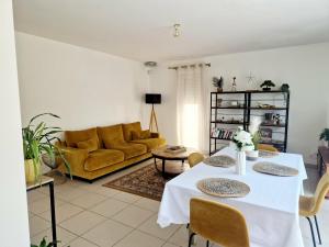 a living room with a table and a yellow couch at Villa Cosy T5, Calme avec Jacuzzi XL in Nîmes