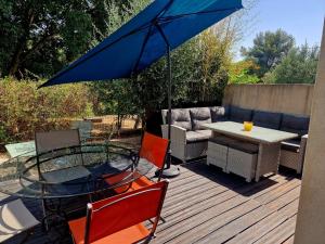 a patio with a table and a blue umbrella at Villa Cosy T5, Calme avec Jacuzzi XL in Nîmes