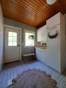 una cucina con mobili bianchi e soffitto in legno di Villa Hammar a Sulkava