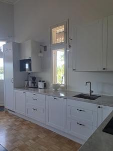 una cucina con mobili bianchi, un lavandino e una finestra di Villa Hammar a Sulkava