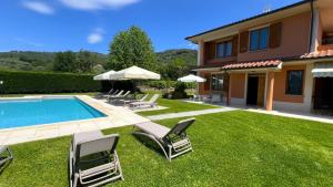 a yard with chairs and a swimming pool and a house at Villino Blu 12 pax villa in Tuscany with private pool in Loro Ciuffenna