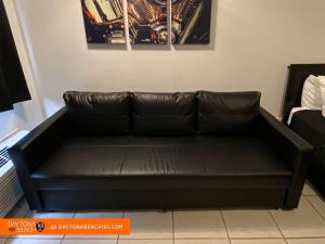 a black leather couch sitting in a room at Amazing Studio Steps Away From The Atlantic Ocean! in Daytona Beach