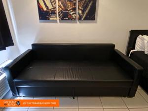 a black couch in a room with a painting at Amazing Studio Steps Away From The Atlantic Ocean! in Daytona Beach +3 photos