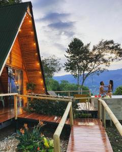 Dos personas de pie en el porche de una casa de madera. en Valle Verde Eco, en Riofrío