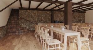 Habitación con mesas, sillas y pared de piedra. en My Rooms Hostel Las Salas by My Rooms Hotels - Albergue, en Las Salas