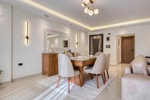 a dining room with a table and chairs and a mirror at Luxurious 3Bd Hotel Apt in compound Sheikh Zayed with Pool and Gym access in Sheikh Zayed