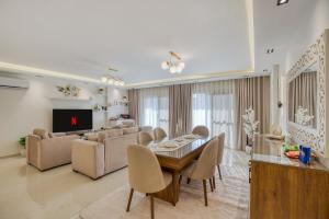 a living room with a table and chairs and a television at Luxurious 3Bd Hotel Apt in compound Sheikh Zayed with Pool and Gym access in Sheikh Zayed