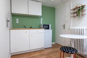 a kitchen with white cabinets and a white table at Studio de Luxe Entièrement Neuf - Proche Paris in Gagny