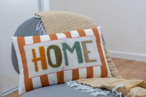 a home pillow with the word home on it on a chair at Studio de Luxe Entièrement Neuf - Proche Paris in Gagny