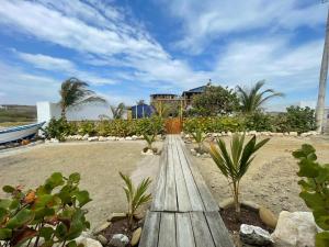 Un Dia Boutique Resort في بلاياس: جسر خشبي على الشاطئ مع منزل في الخلفية