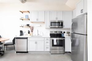 Brewery District 2-Story 2BR Apt Near Fiserv with Rooftop, Gym, and Parking في ميلووكي: مطبخ بخزائن بيضاء وثلاجة من الفولاذ المقاوم للصدأ