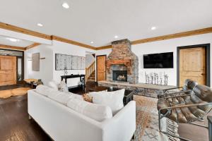 a living room with white furniture and a stone fireplace at Wild Horse Meadows Eden Powder Mtn in Wolf Star