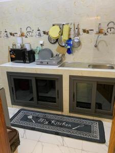 Keur MAME TAWFEKH في Thies: مطبخ مع طاولة وحوض وسجادة مطبخ