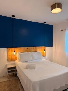 ein Schlafzimmer mit blauem Kopfteil und weißem Bett in der Unterkunft Pituba Ville - Ap - 1 andar - 2/4 in Itacaré