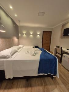 a bedroom with a large white bed with a blue blanket at Pousada Vale do Chapéu in Capitólio