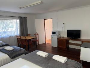 Habitación con 2 camas y mesa con TV. en Restawile Motel, en Busselton