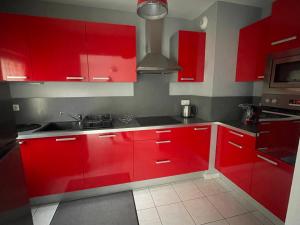 a red kitchen with red cabinets and a sink at À deux pas de la mer in Marennes