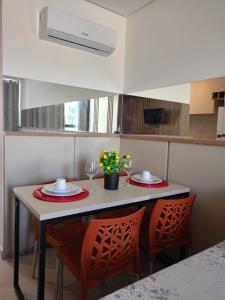 a small kitchen with a table with two chairs and flowers at Aquach Beach Residence in Tamandaré