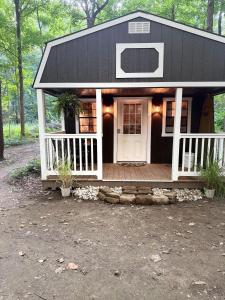 ein kleines schwarzweißes Haus mit einer Veranda in der Unterkunft Creekwood Cottage in Peru