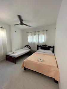 a bedroom with two beds and a ceiling fan at Hotel Casa Colonial Moñitos in Moñitos