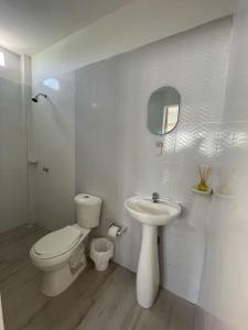 a white bathroom with a toilet and a sink at Hotel Casa Colonial Moñitos in Moñitos