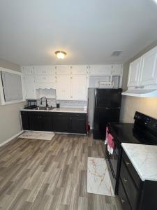 8mins from Jaguar stadium & the Historical Riverside في جاكسونفيل: مطبخ به اجهزه سوداء وارضيات خشبية