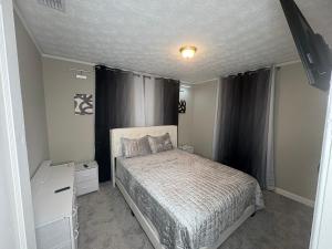 8mins from Jaguar stadium & the Historical Riverside في جاكسونفيل: غرفة نوم بسرير وستارة سوداء