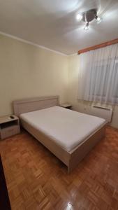 a bedroom with a large white bed and a window at Apartman Mimi in Bratunac