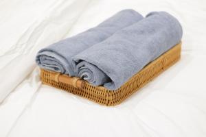 a wooden basket with towels on a bed at House of Keul - 2BR cozy condo in Dumaguete with pool and free laundry for long term guests up to 4 pax in Piapi +21 photos