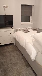 Victorian Suites Apartment في ساوثبورت: غرفة نوم مع سرير وخزانة مع تلفزيون