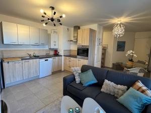a living room with a couch and a kitchen at Appartement cosy et confortable à deux pas du lac in Excénevex