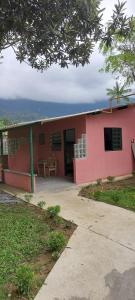 Hostel33 brazil praia في كاراغواتاتوبا: مبنى وردي اللون به شرفة وطاولة