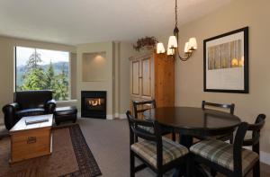 a living room with a table and chairs and a fireplace at The Marquise by Whistler Premier in Whistler