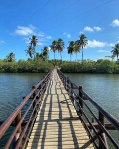 a wooden bridge over a river with palm trees at Casa em Porto de pedras in Tatuamunha