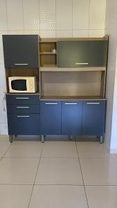 a kitchen with blue cabinets and a microwave at Casa em Porto de pedras in Tatuamunha